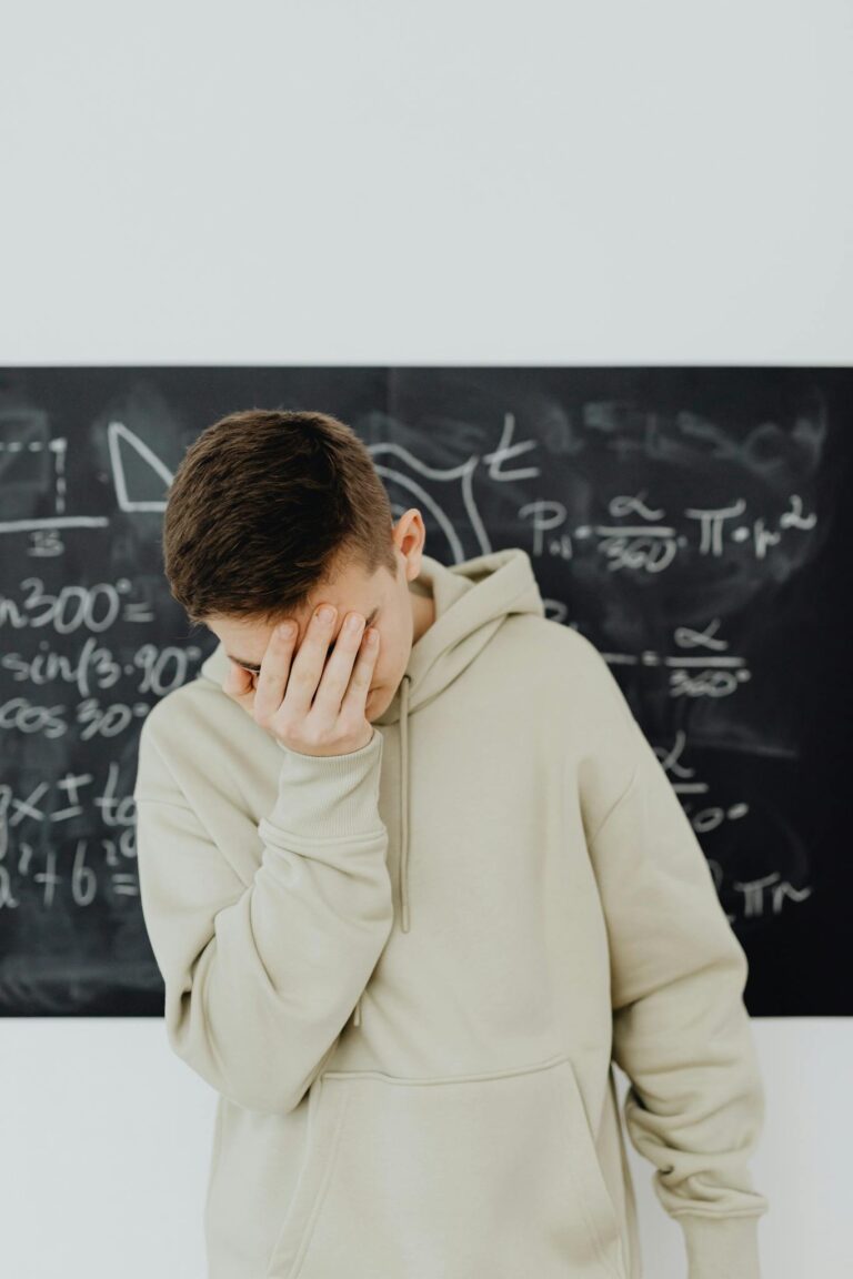 A young man stands in front of a blackboard, looking frustrated amidst complex calculations.